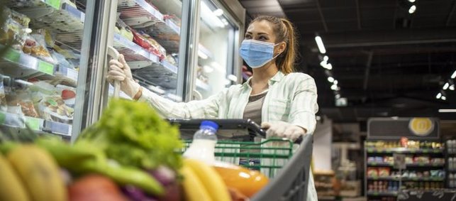 Ein Frau mit einer Mund-Nasen-Schutz-Maske beim Einkaufen im Supermarkt