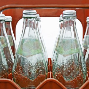 leere Mehrwegwasserflaschen aus Glas in einem Kasten