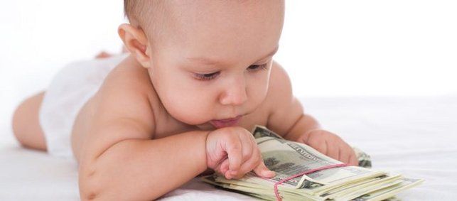Ein Baby liegt vor einem Bündel von Geldscheinen