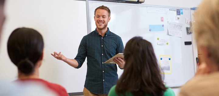 Junger Lehrer unterrichtet vor einem Whiteboard