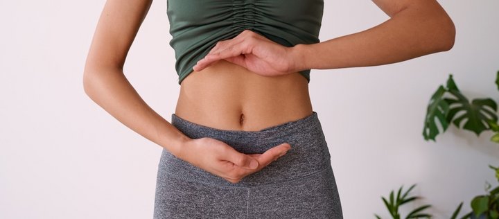 Eine Frau zeigt mit den Händen ihren Bereich des Bauch Magen und Darm