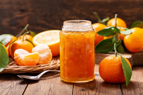 Marmelade im Glas, umgeben von Mandarinen