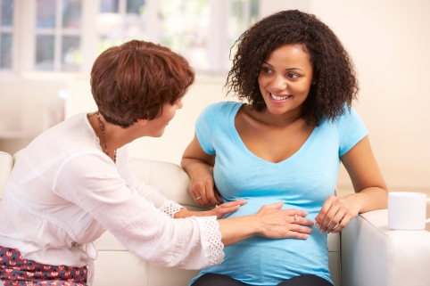 Eine Hebamme spricht mit einer schwangeren Frau und gibt ihr eine Info-Broschüre.