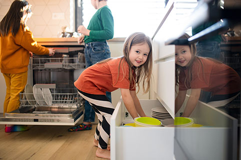 Eine Frau und zwei Kinder helfen beim Ausräumen der Spühlmaschine.