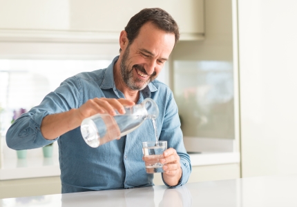 Ein Mann gießt sich ein Glas Wasser in ein.