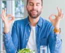 Mann vor Salat mit geschlossenen Augen presst Zeigefinger auf Daumen