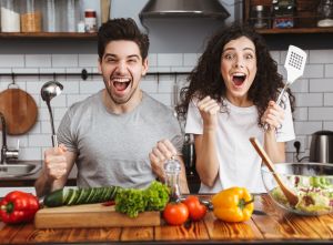 Frau und Mann haben Spaß in der Küche mit Gemüse