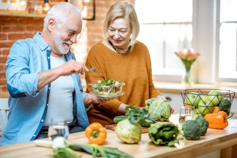 Bild: Ein älteres Paar bereitet einen Salat zu.