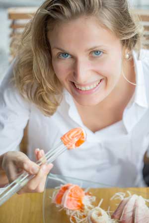 Frau isst Fisch mit Essstäbchen
