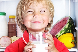 Junge mit Glas Milch in der Hand grinst