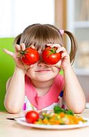 Mädchen hält sich Tomaten vor die Augen