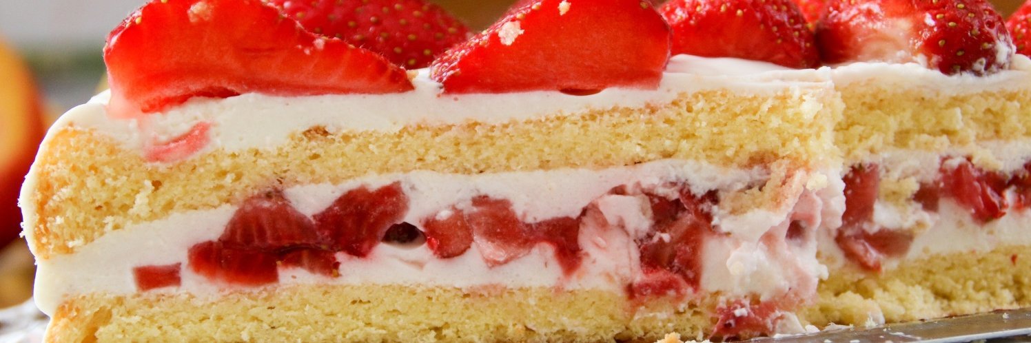 Eine angeschnittene Biskuittorte mit Cremefüllung und Erdbeeren als Füllung und als Dekoration.