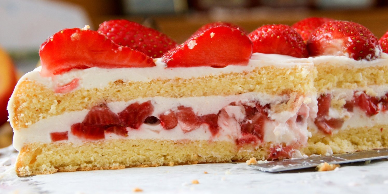 Eine angeschnittene Biskuittorte mit Cremefüllung und Erdbeeren als Füllung und als Dekoration.. Artikel "Lust auf leichte Sommerkuchen" öffnen.