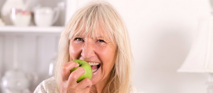 Ein ältere Frau beißt in einen Apfel