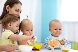 Drei Kleinkinder und eine Betreuerin beim Essen