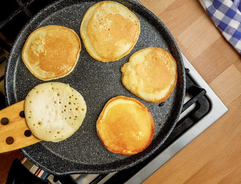 In einer schwarzen Pfanne liegen fünf kleine Pfannkuchen.