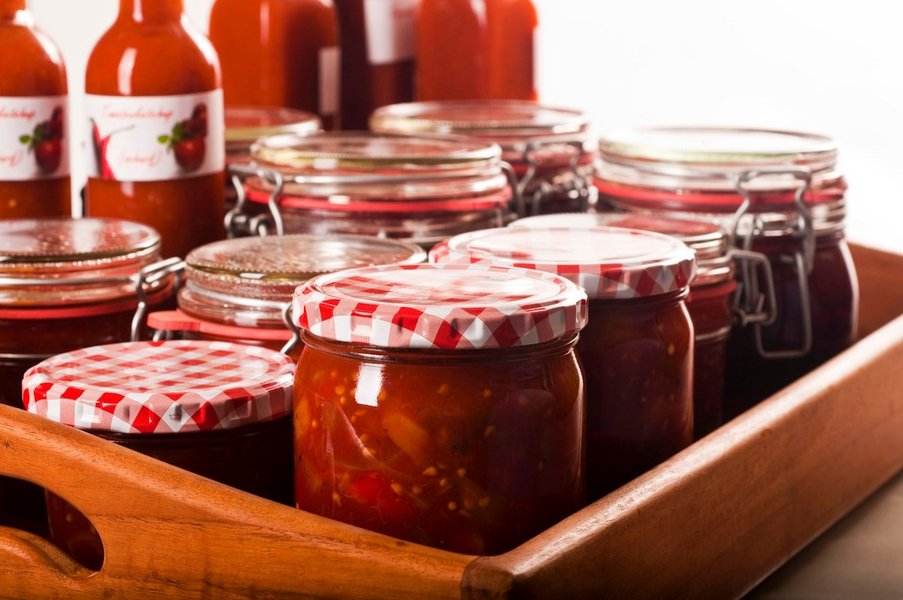 Mehrere Gläser und Flaschen mit eingekochtem Tomatenketchup stehen auf einem Tablett.