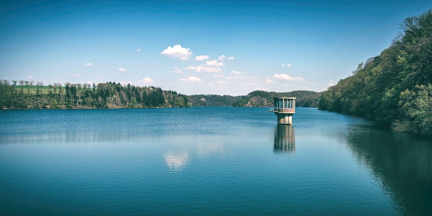 Eine große Talsperre mit dem Entnahmeturm für Trinkwasser rechts.