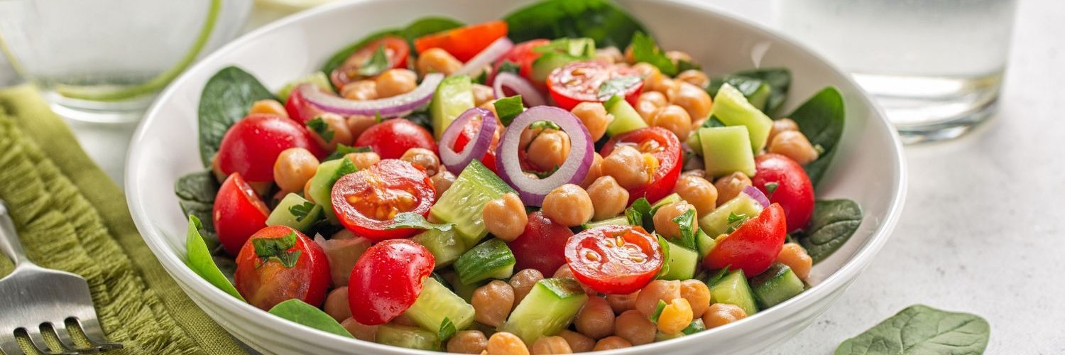 Mediterraner Salat mit Kichererbsen, Tomaten, Gurken, Spinat und roten Zwiebeln.
