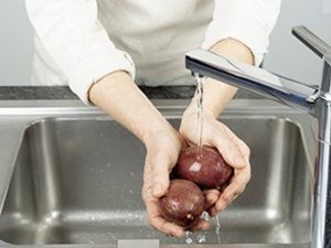 Eine Person wäscht Passionsfrucht unter fließendem Wasser.