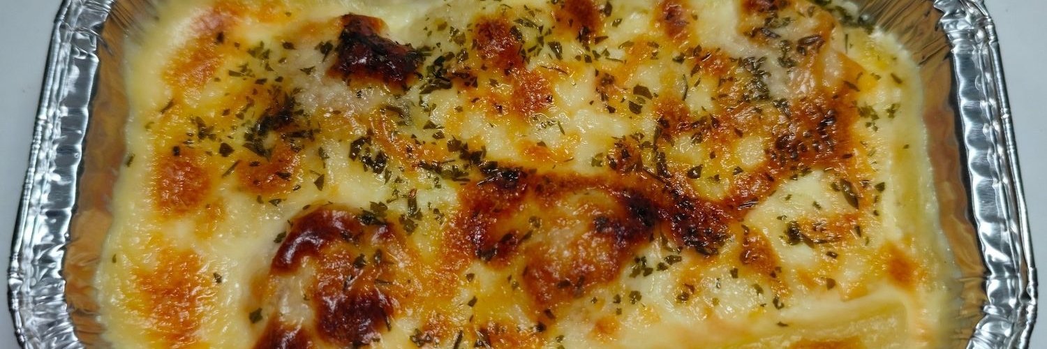 Ein mit Käse überbackenes Fertig-Pastagericht liegt in einer Aluschale. 