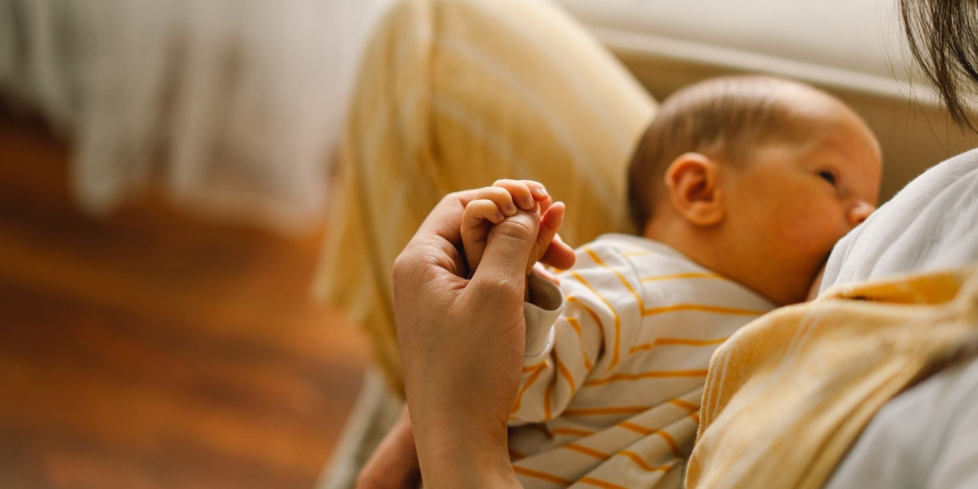 Ein Baby liegt an der Brust der Mutter. Die Mutter hält die Hand des Babys.. Artikel "Stillen: Tipps für einen guten Start" öffnen.