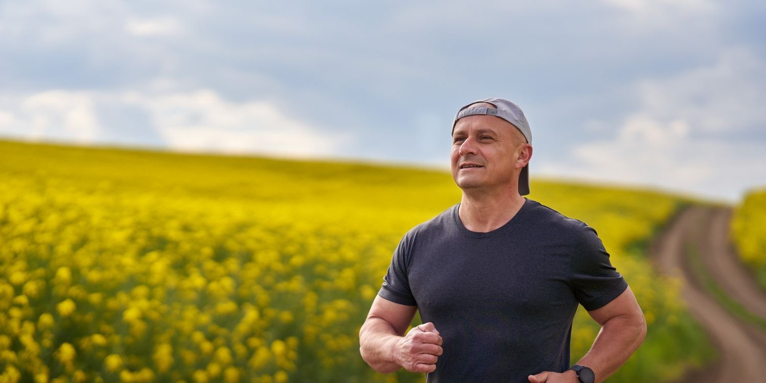 Ein Jogger läuft auf einem Feldweg an einem Rapsfeld entlang.. Artikel "Rapsöl: Gesundheit und Umwelt" öffnen.