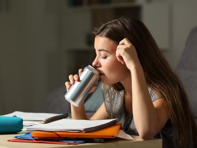 Ein Schulkind trinkt aus einer Dose Energy-Drink.