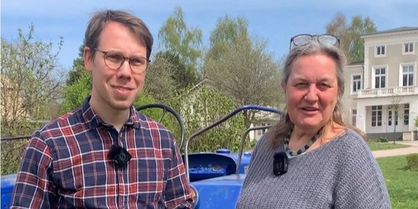 Ein Mann und eine Frau stehen vor einm Traktor.