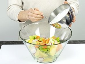 eine Person gibt das Salatdressing zum Salat.