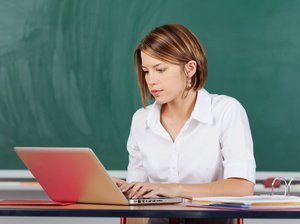 Lehrerin am Laptop vor einer Schultafel