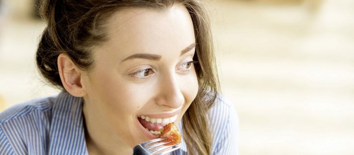Junge Frau hält Gabel mit Tomatenstück vor den Mund