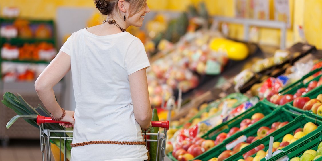Junges Mädchen schiebt einen Einkaufwagen durch die Obst- und Gemüseabteilung eines Supermarkts.. Artikel "Obst- und Gemüsevielfalt entdecken" öffnen.