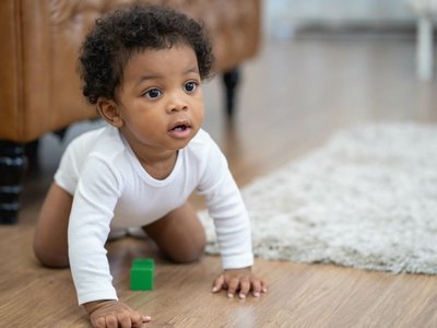 Ein Baby krabbelt auf dem Boden.