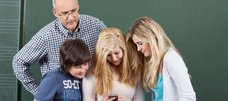 Lehrer und Schüler schauen auf ein Smartphone