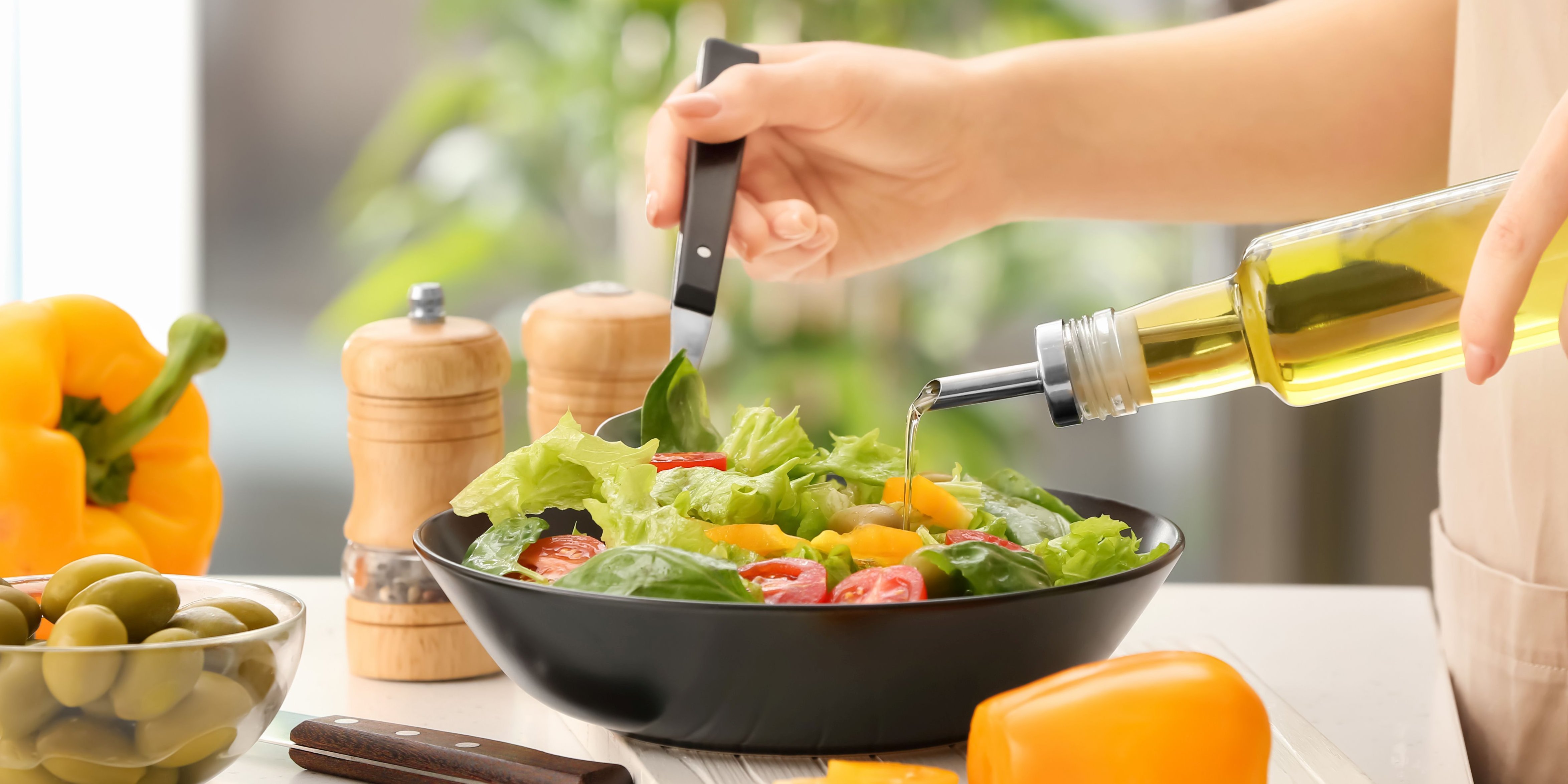 Frau gibt Öl aus Glasflasche an Blattsalat.. Artikel "Fett – wichtiger Energielieferant und Nährstoff  " öffnen.