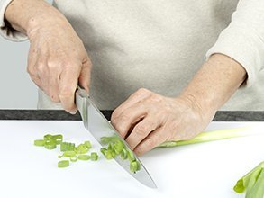 Person schneidet Lauchzwiebeln in feine Ringe.