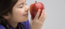 Mädchen riecht an einem Apfel