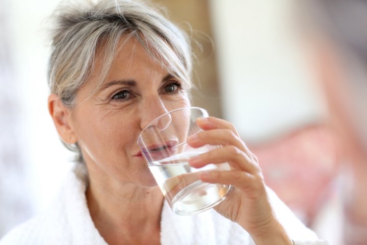 Eine Frau trinkt ein Glas Wasser.