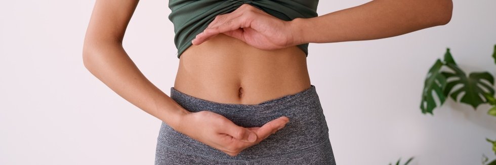 Eine Frau zeigt mit den Händen ihren Bereich des Bauch Magen und Darm
