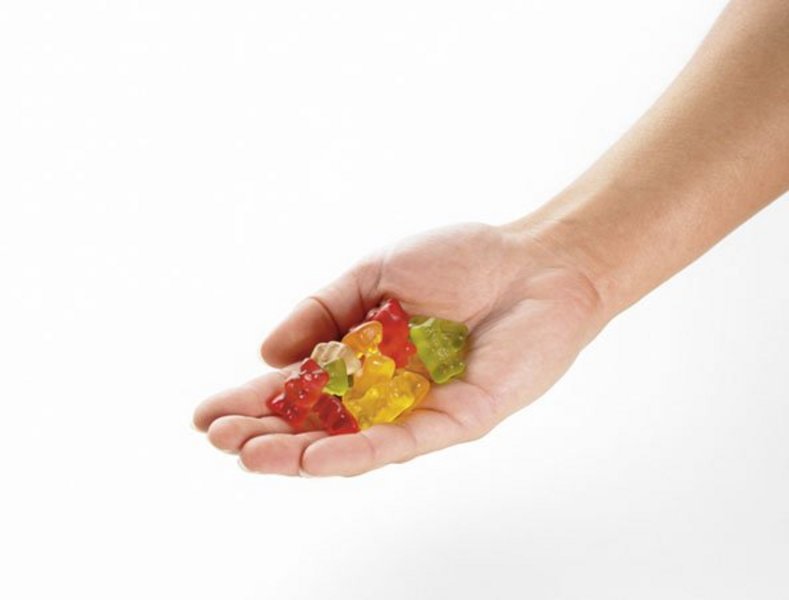 Eine Erwachsenenhand ist gefüllt mit Gummibärchen.