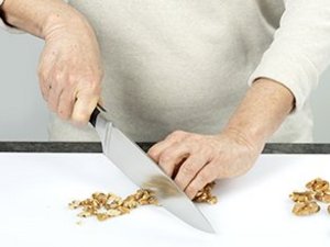 Eine Person hackt Nüsse mit Messer.