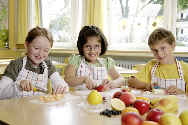 Drei Kinder schneiden Obst