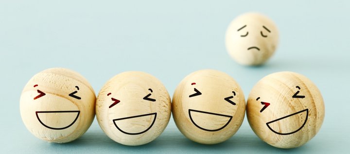 Vier Bälle mit lachendem Gesicht im Vordergrund und ein Ball mit traurigem Gesicht im Hintergrund