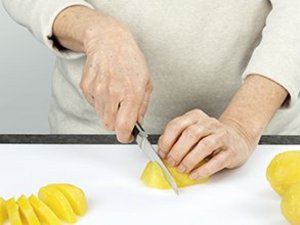 eine Person schneidet die Kartoffeln.