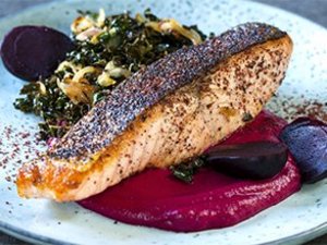 Rote Bete mit Kartoffelpüree und Fisch auf einem Teller.