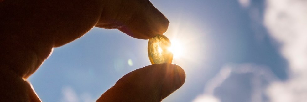 Eine Person hält eine Nahrungsergänzungspille in den Händen und hält diese in die Sonne