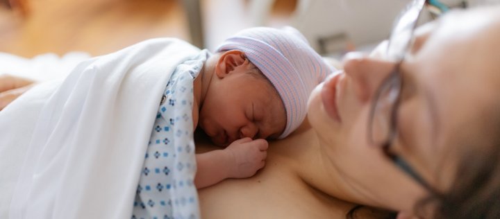 Ein Neugeborenes liegt auf der Brust seiner Mutter