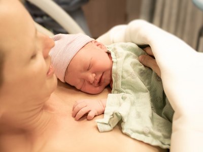 Ein neugeborenes Baby liegt auf der Brust der Mutter. 