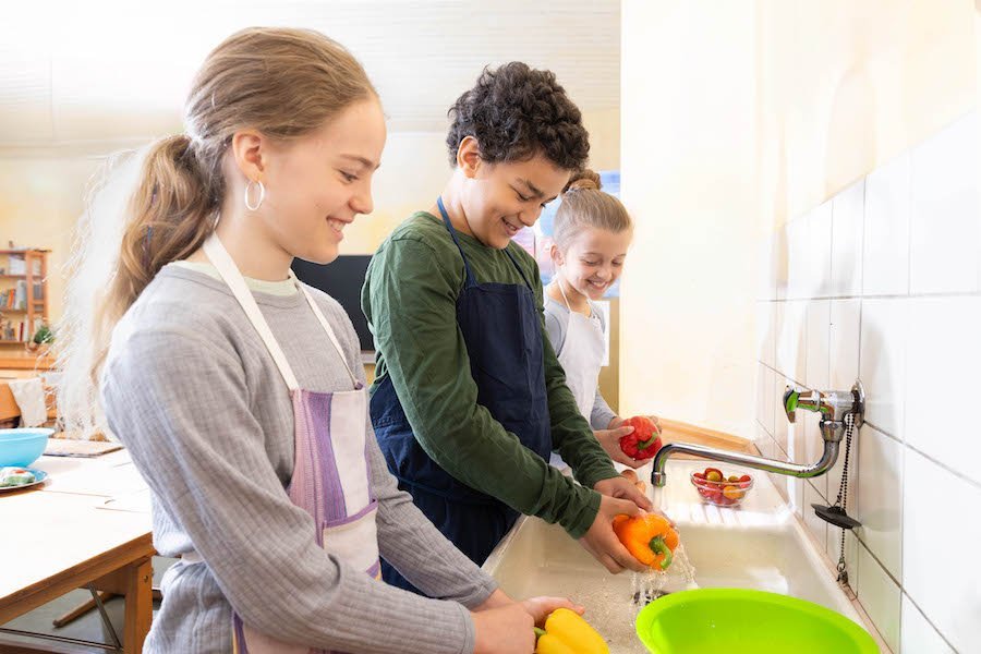 Ein Schüler und eine Schülerin waschen Paprikaschoten .